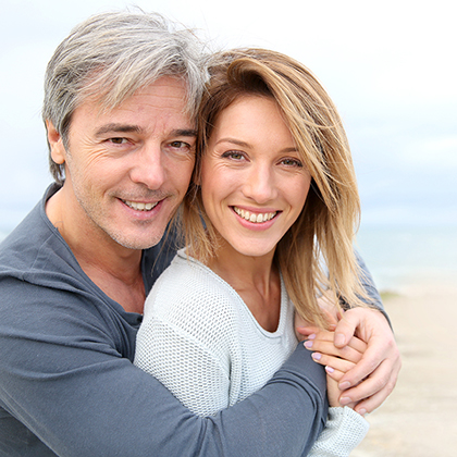 Cheerful mature couple embracing by the beach