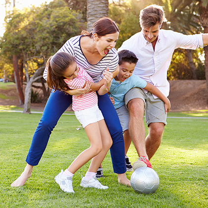 Family Playing Soccer In Park Together